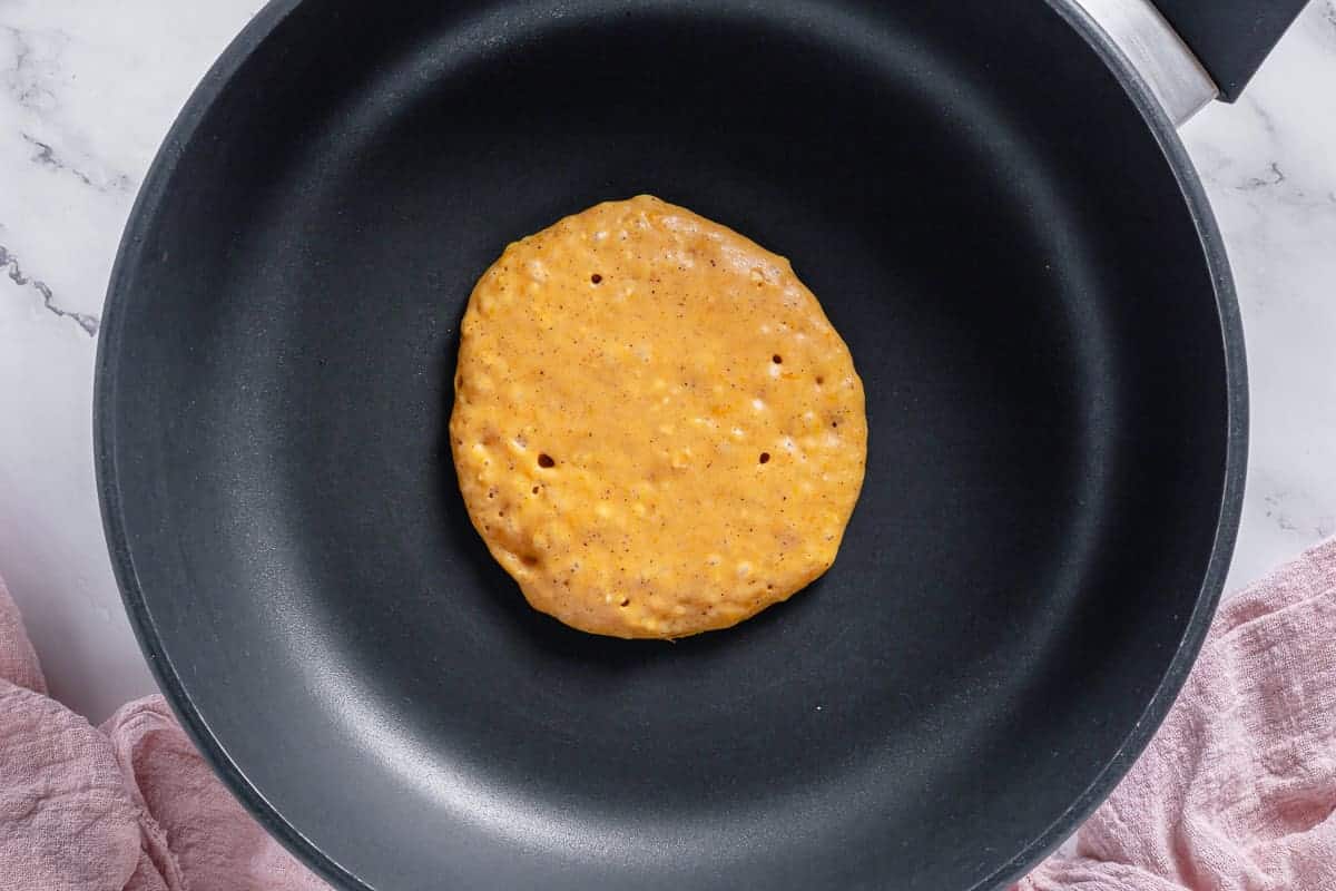 pumpkin pancake batter scooped on a non stick pan