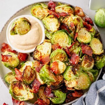 air fryer brussel sprouts with bacon and parmesan on a plate with chipotle aioli sauce