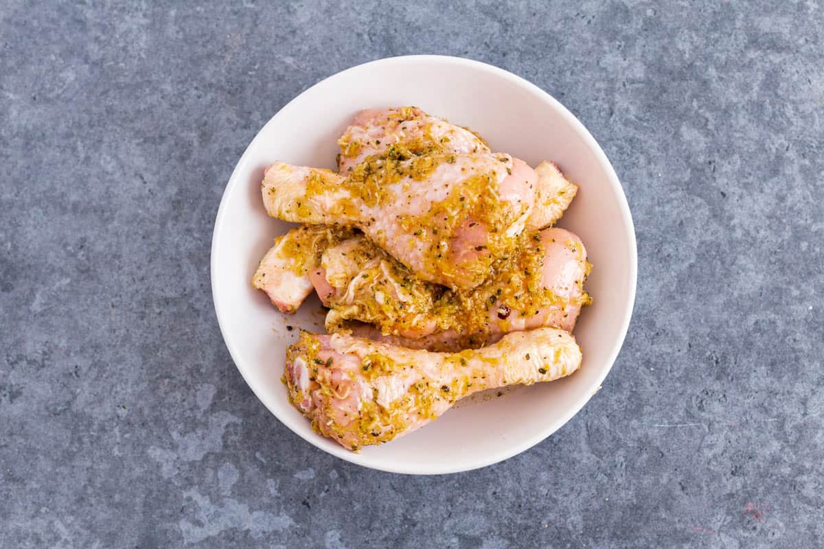 chicken legs in lemon garlic marinade in a bowl before air frying