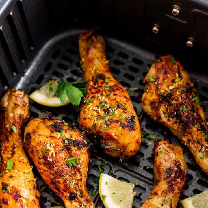 chicken legs in lemon garlic marinade in air fryer basket after cooking