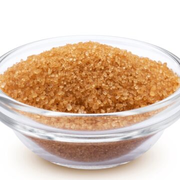 Glass bowl filled with coarse brown sugar crystals on a white background, illustrating brown sugar substitutes for baking.