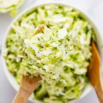 Flat lay shot of Cabbage and Cucumber salad with dill in a white bowl