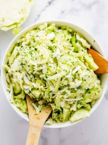 Flat lay shot of Cabbage and Cucumber salad with dill in a white bowl