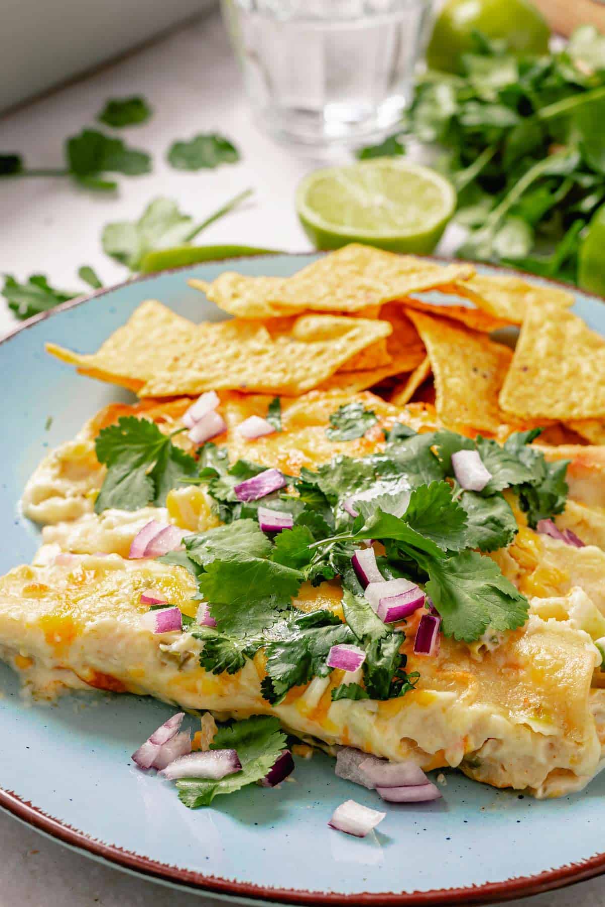 two enchiladas on a blue plate served with with tortilla chips