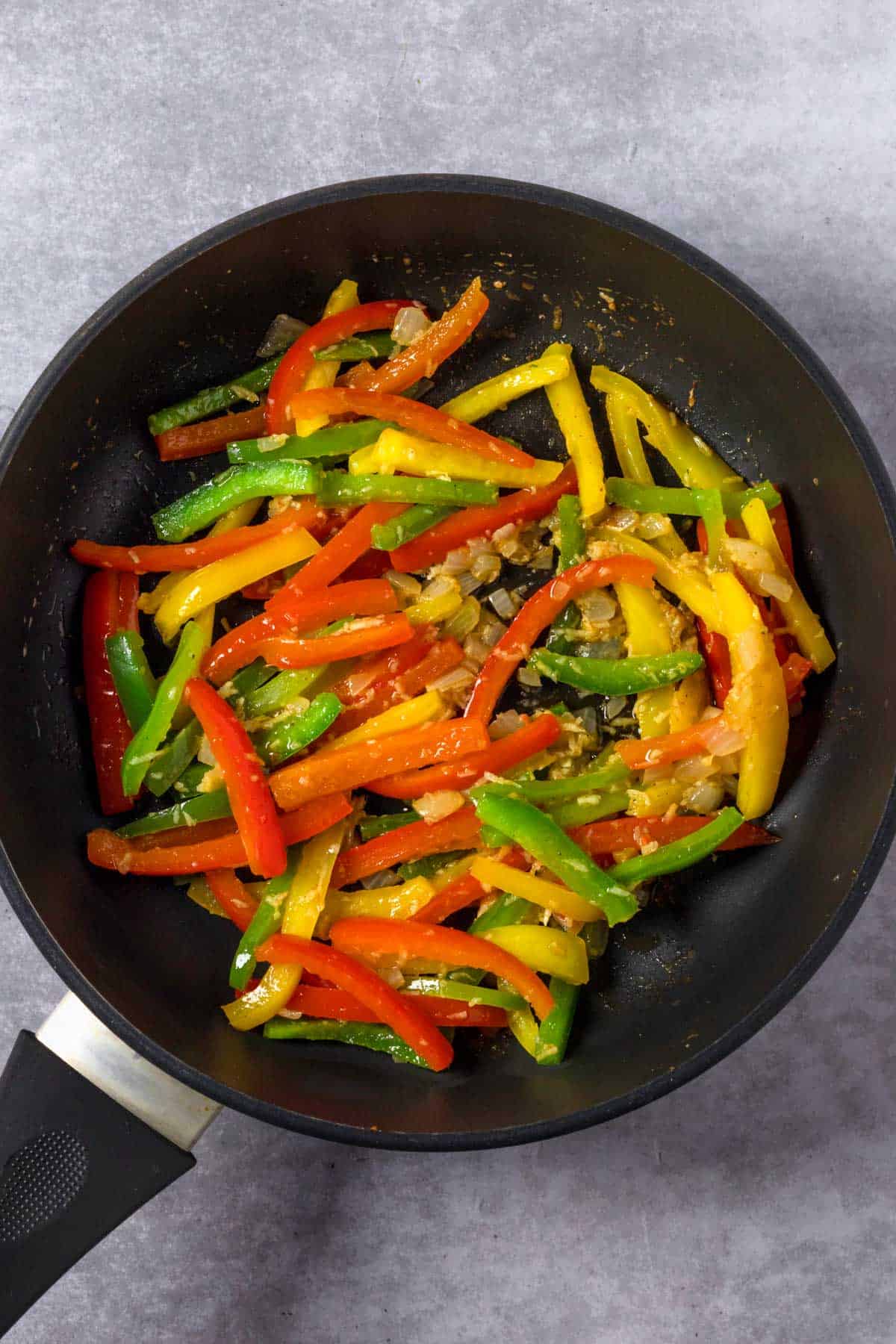 bell peppers and onions cooking in a skillet