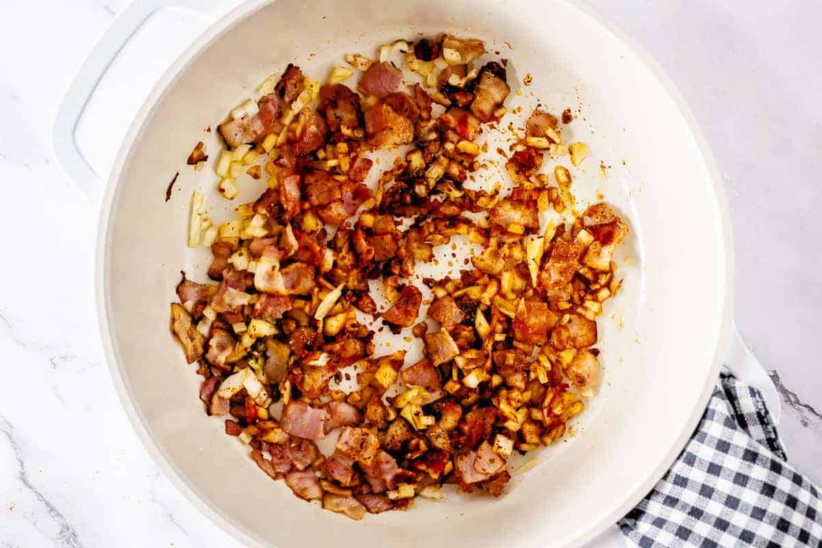 Bacon, onion and spices sauteeing in a white pot