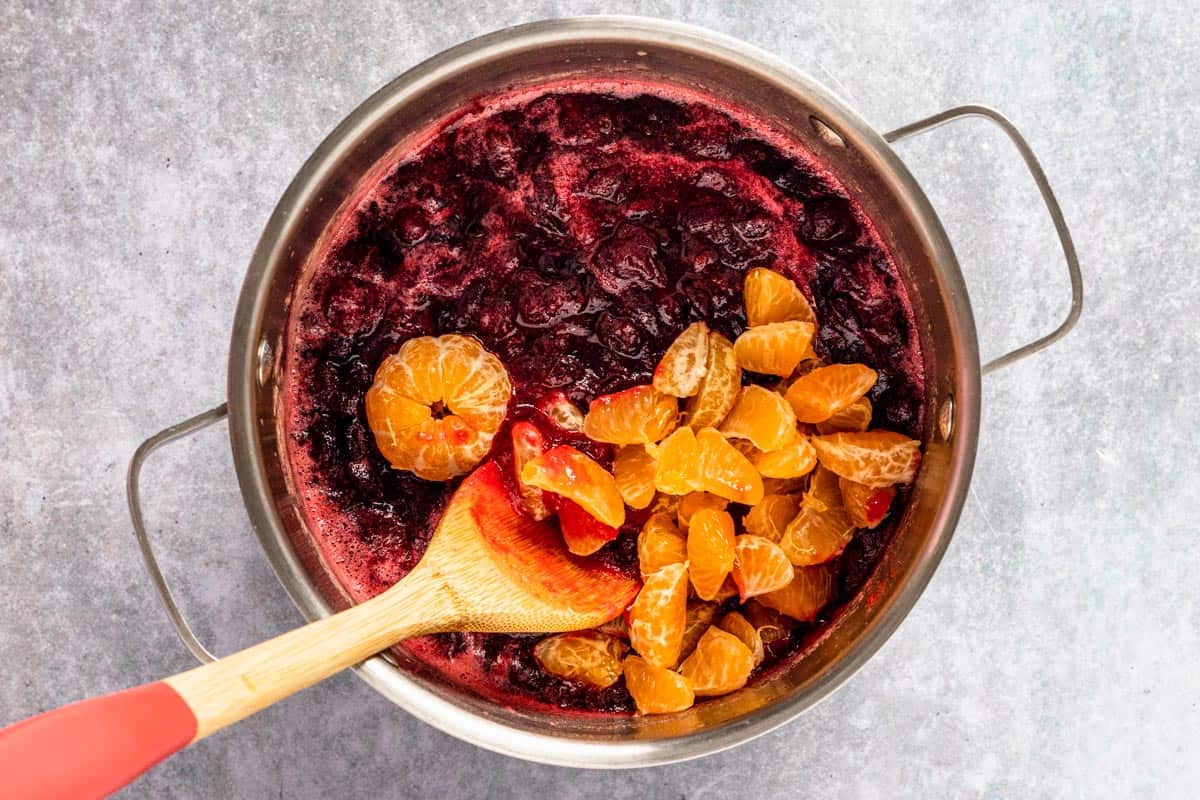 oranges added in a pot with cranberry sauce