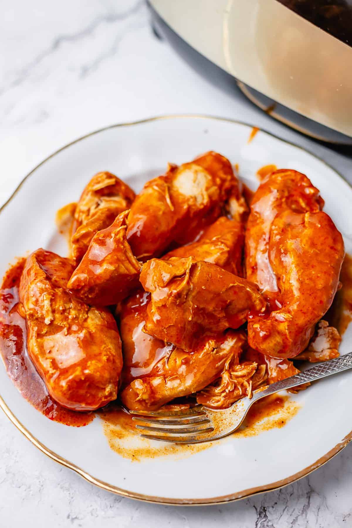 chicken breasts in enchilada sauce on a white plate against marble background