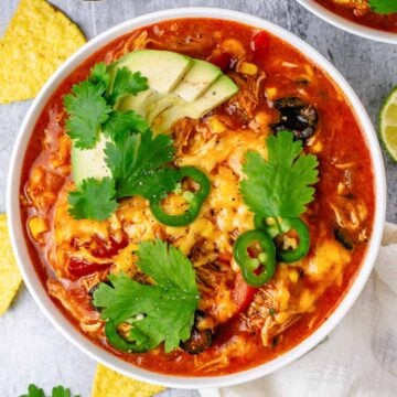 chicken enchilada in a white bowl with avocado jalapeno and tortilla chips
