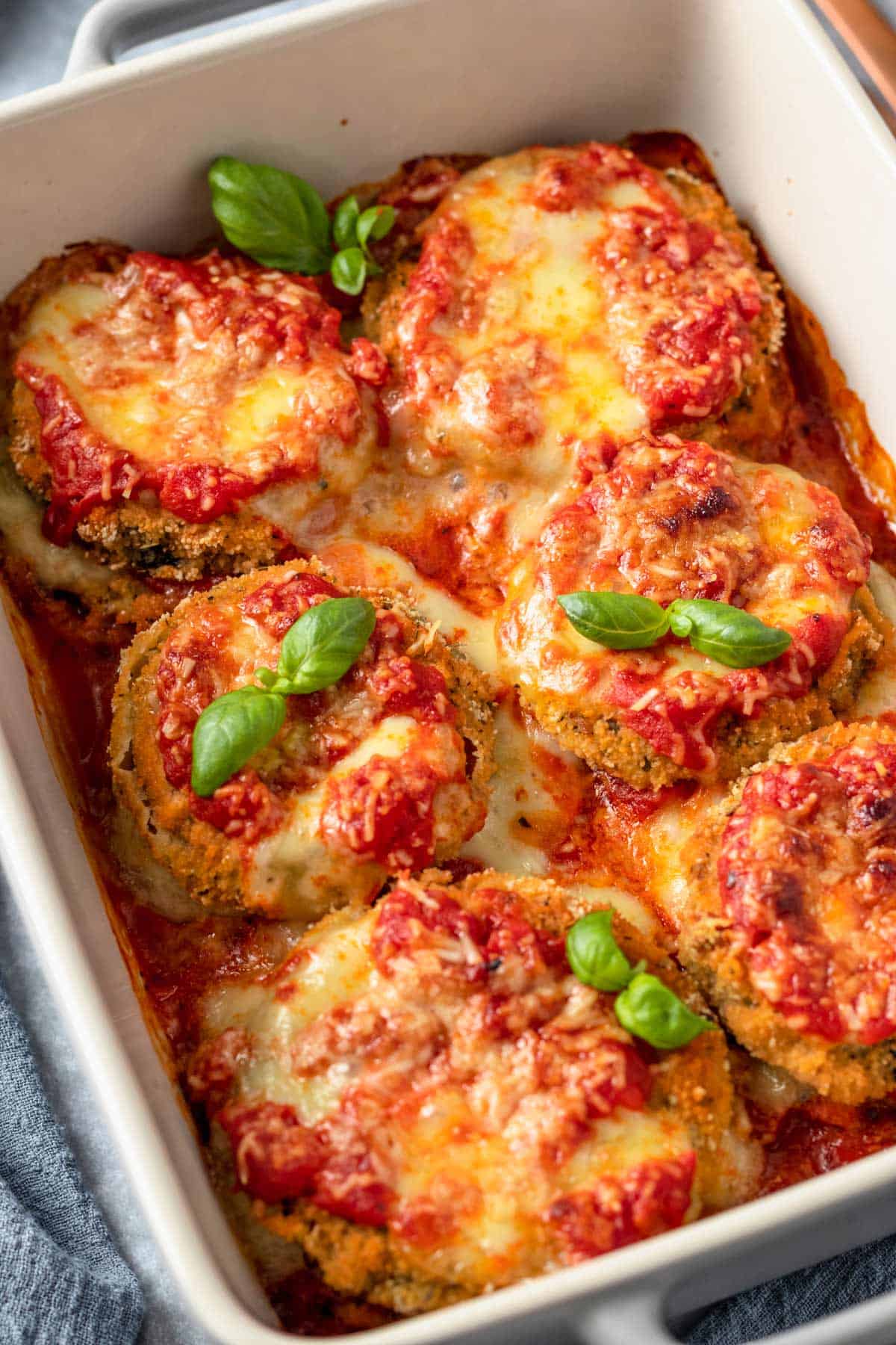 Gluten Free Eggplant Parmesan in baking dish with basil leaves