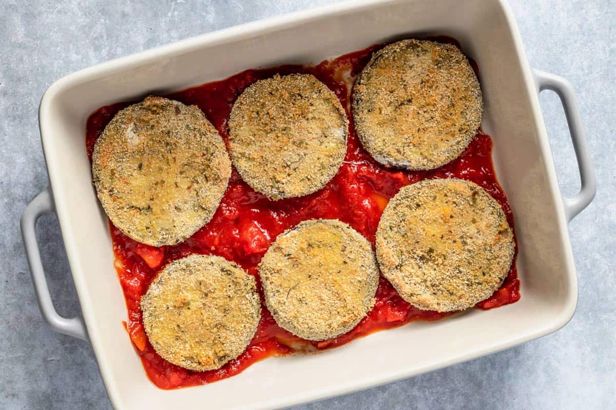 eggplant slices on top of tomato sauce in bakign dish