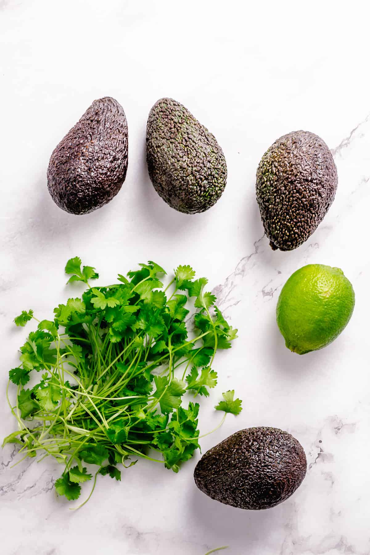 Simple Guacamole recipe ingredients flatlay on a marble background