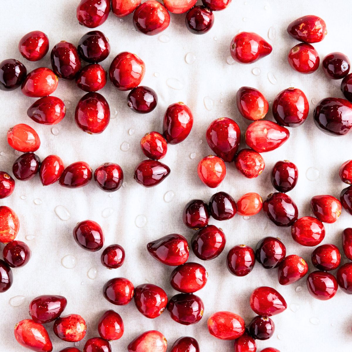 Fresh cranberries scattered across a white background.