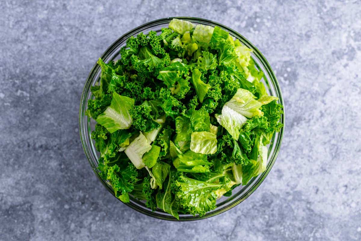 kale and romaine lettuce chunks mixed with the dressing in a bowl