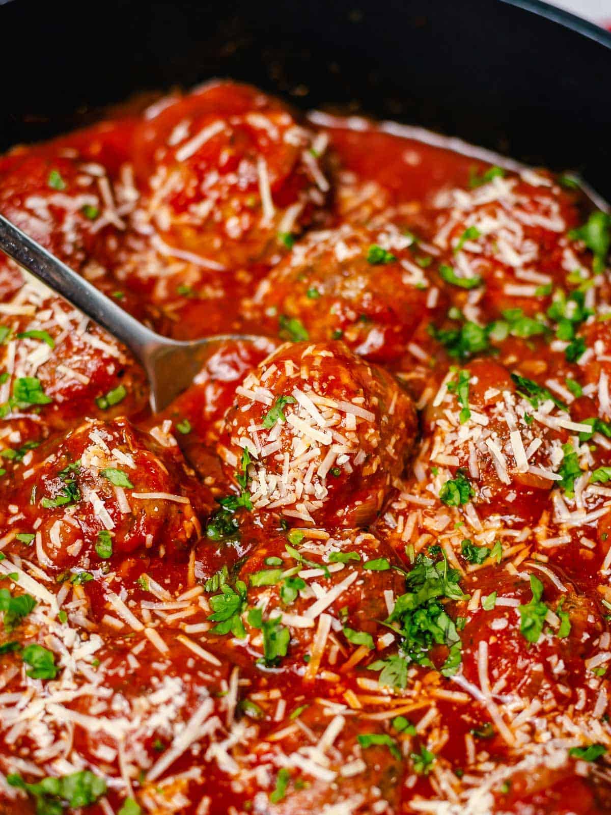 oven baked meatballs simmering in tomato sauce in a black skillet