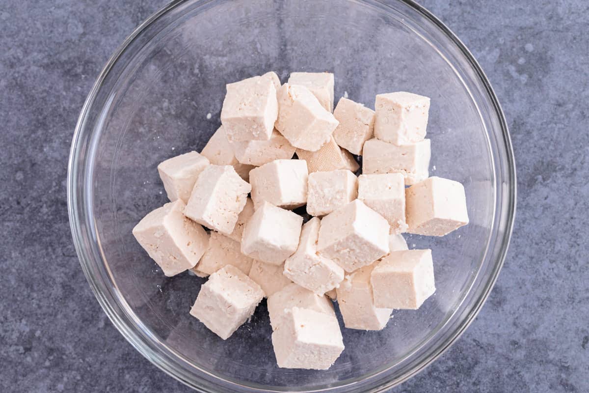 tofu cubes tossed in cornstarch in a mixing bowl
