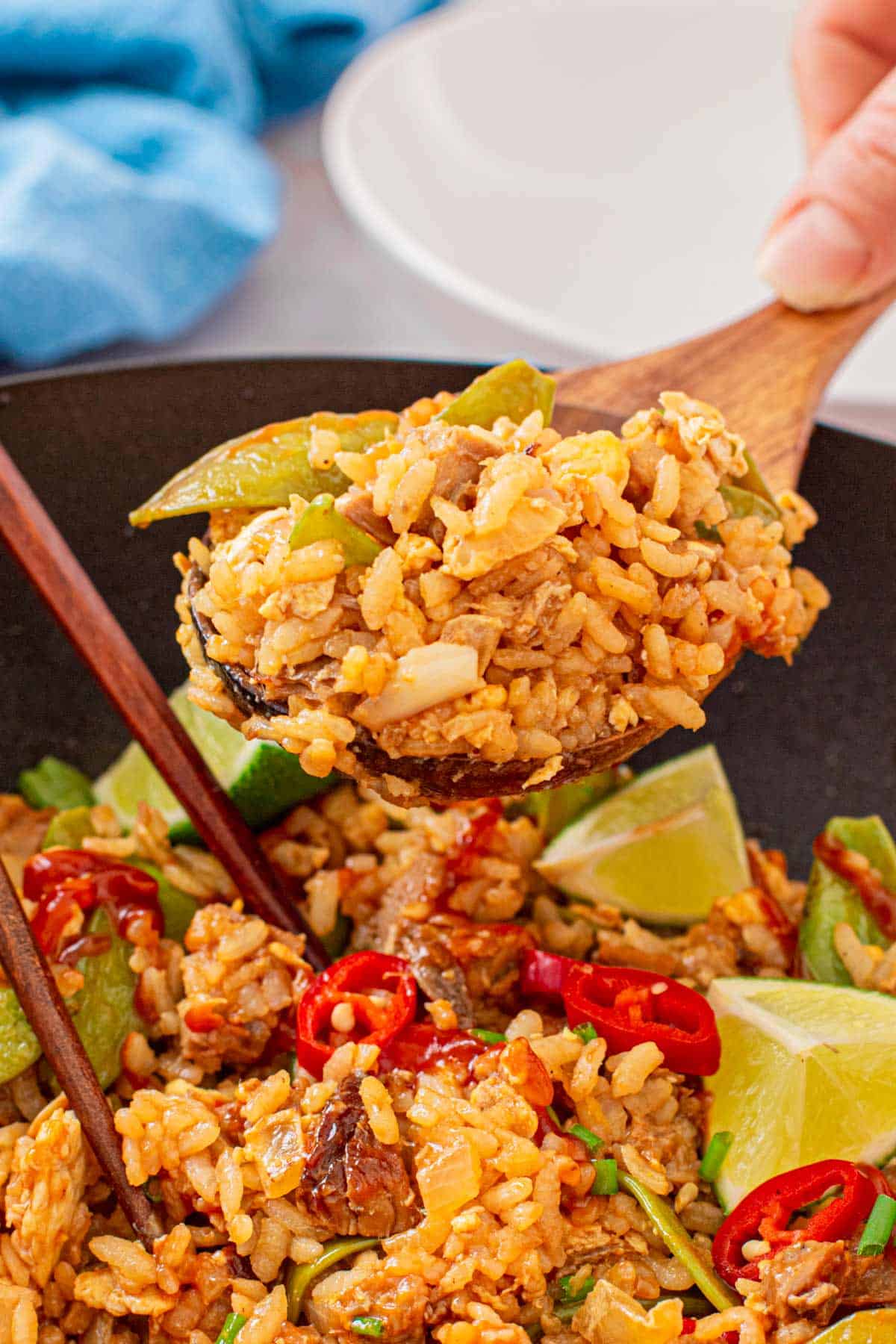 bbq pork fried rice in a wok skillet and a wooden spoon taking out the rice