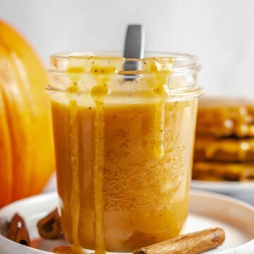pumpkin caramel sauce in a jar with drizzles of sauce on edges over the glass