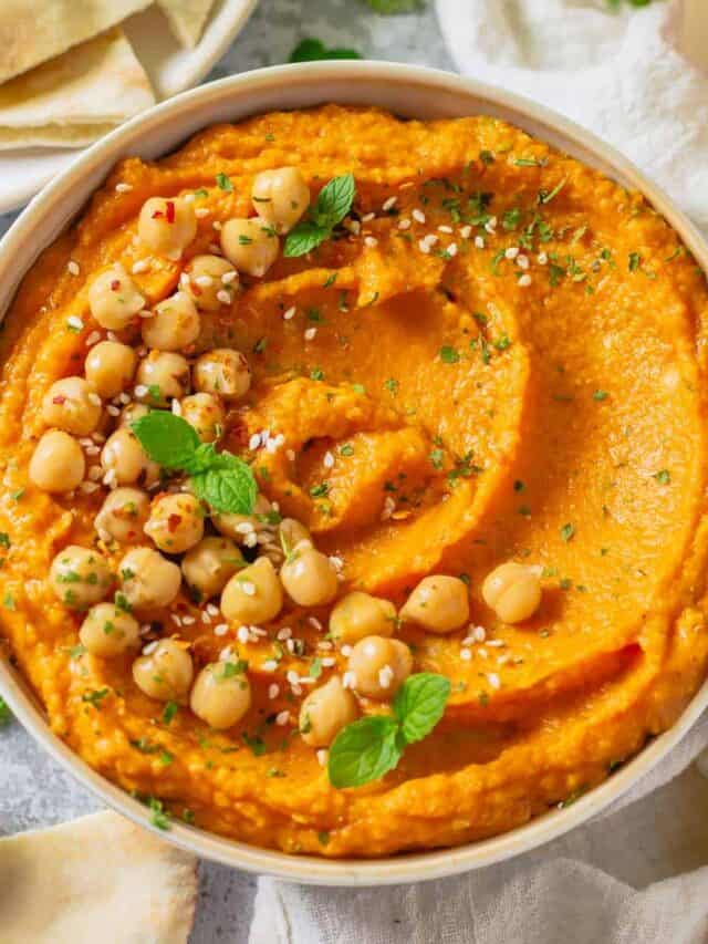 pumpkin and chickpea hummus in a white bowl on a marble table with white linen