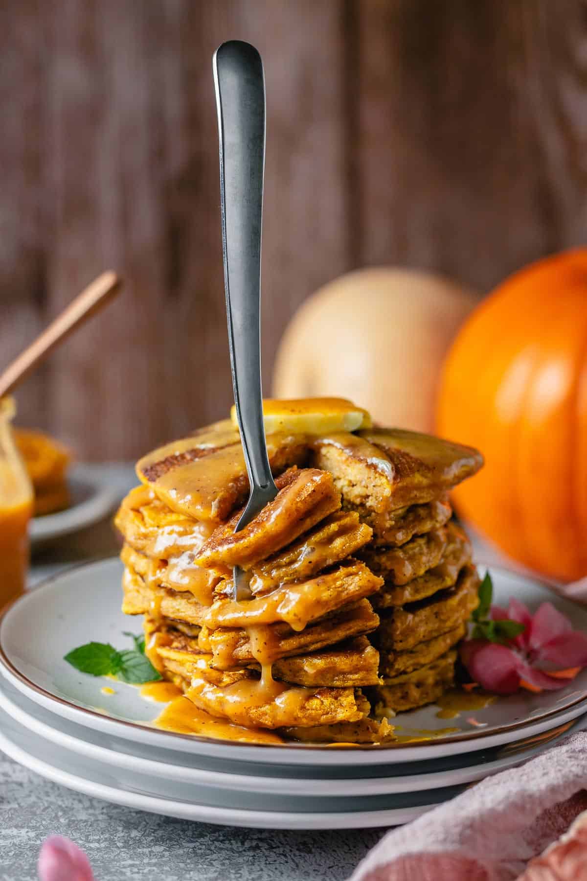 Stacked pumpkin pancakes side view angle with a fork in cut piece