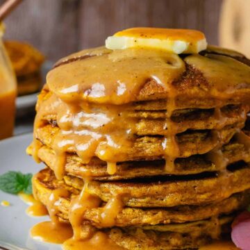 Stacked pumpkin pancakes side view angle with a drizzle of caramel