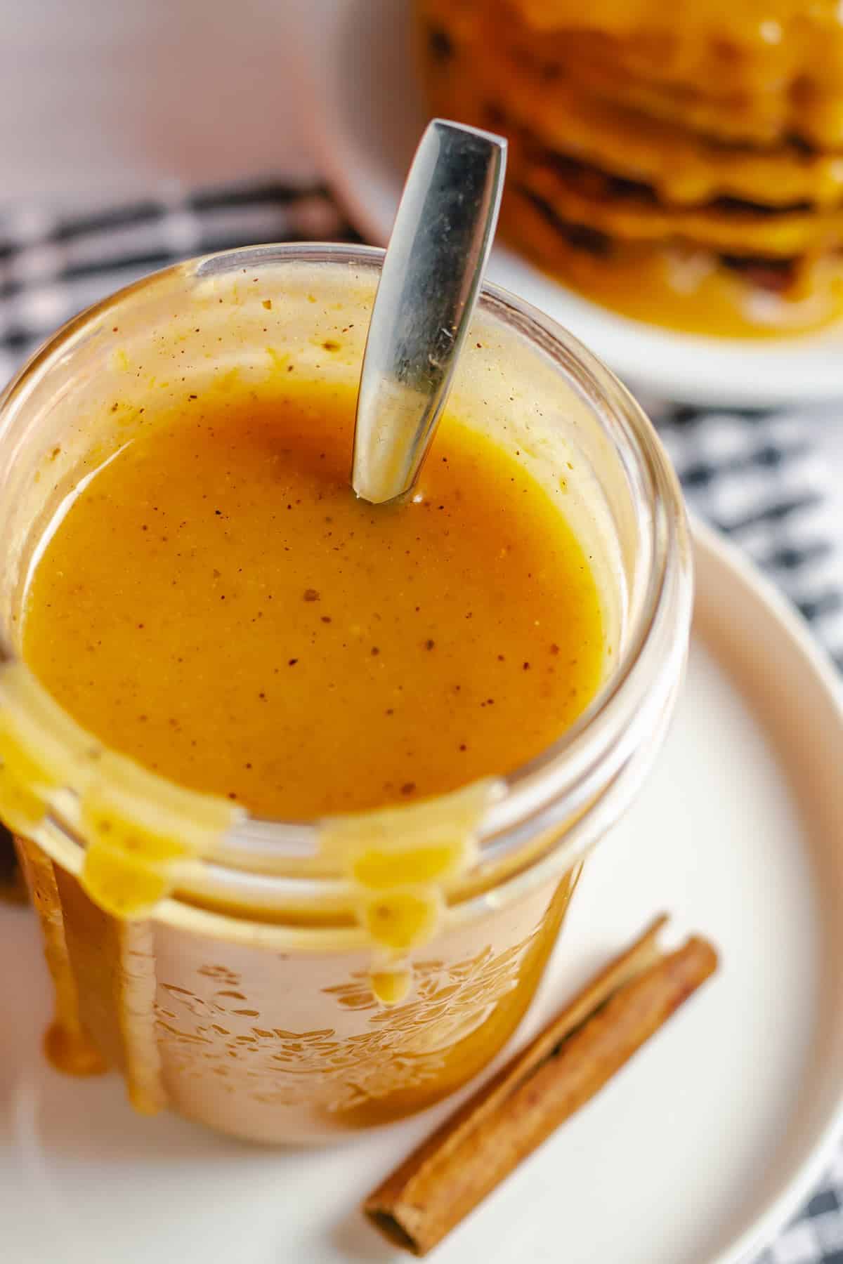 pumpkin caramel sauce in a jar with drizzles of sauce on edges over the glass