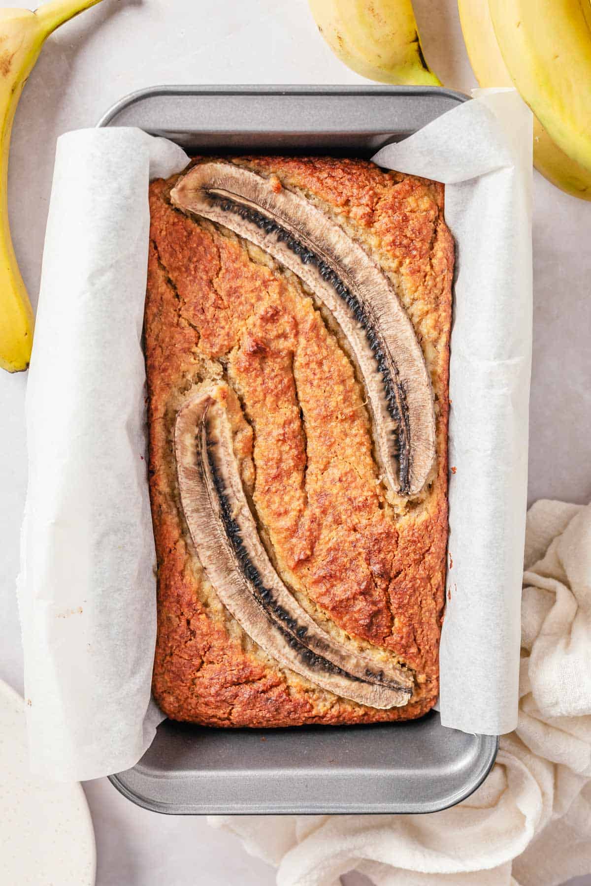 banana bread in loaf pan with banana bread halves on top