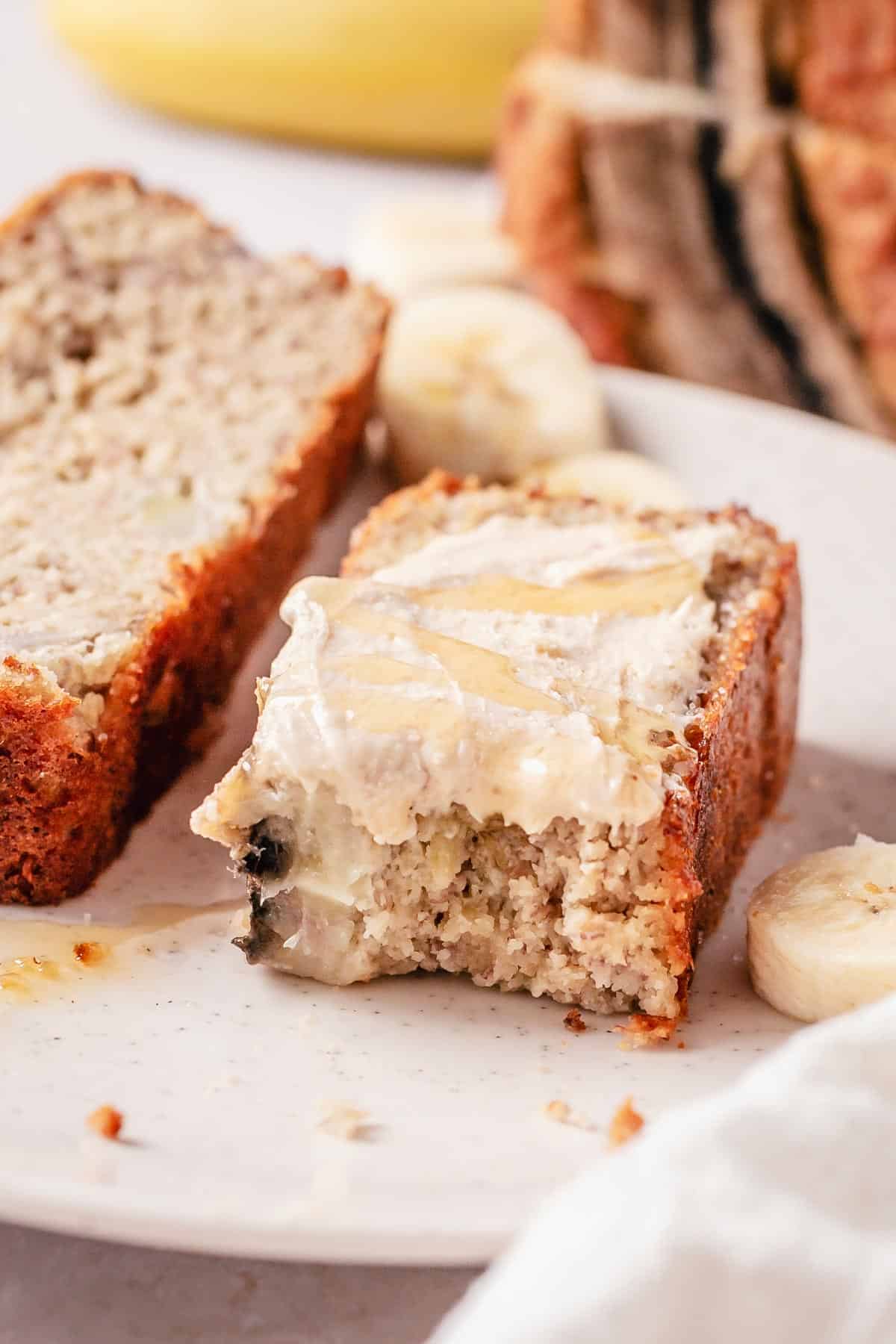 banana bread slices on a plate with almond butter and honey on top