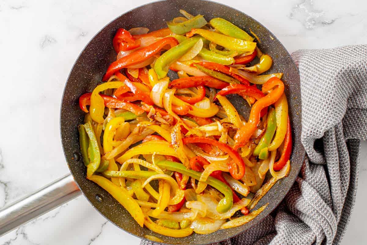 bell peppers and onion saute in a skilet for shrimp fajita