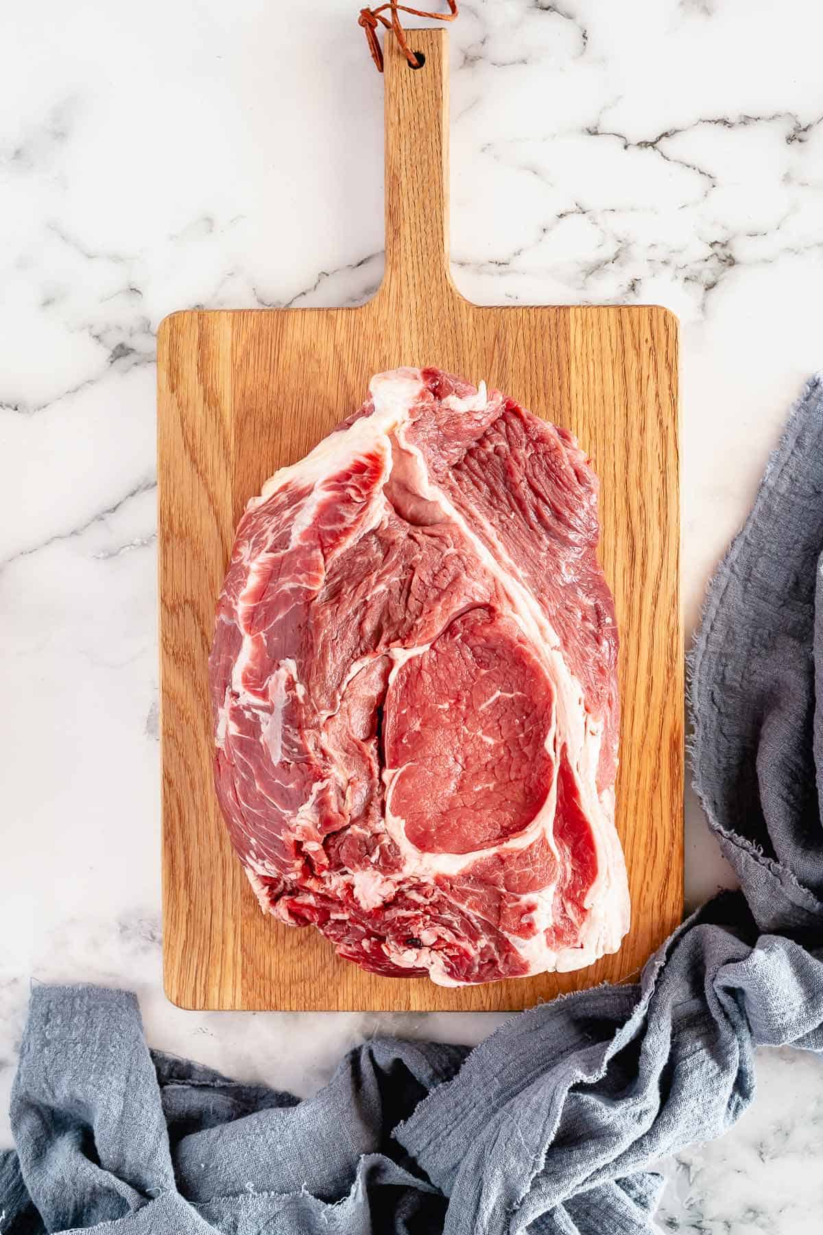 chuck roast on a wooden board white marble background