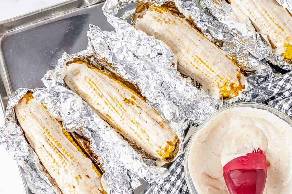Take the corn out from the oven, let cool slightly and brush with leftover oil mixture (optional) and mayo mix all over the corn.