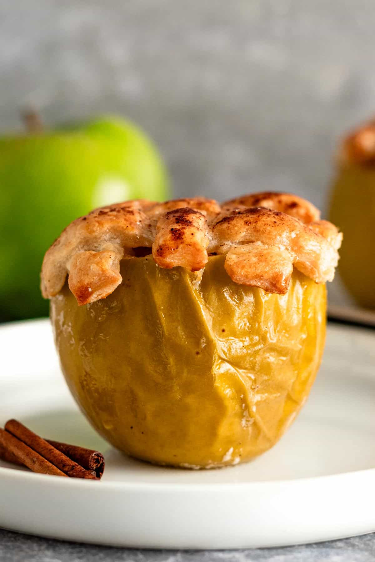 baked green apple on a plate with golden brown dough topping.