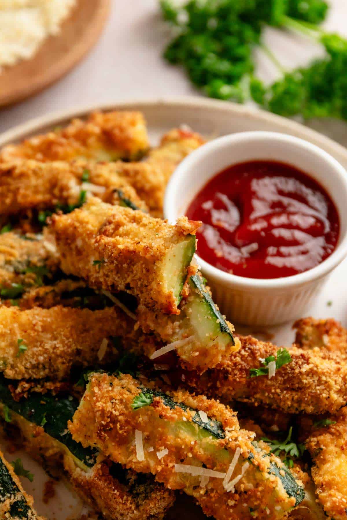 perfectly roasted golden brown zucchini fries served with red sauce.
