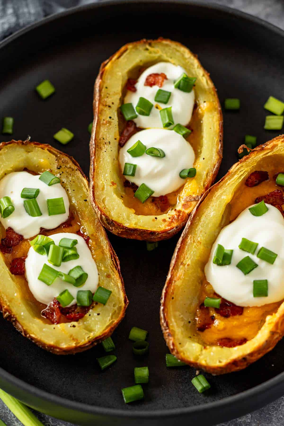 three potato skins with cheese, bacon and sour cream topping.