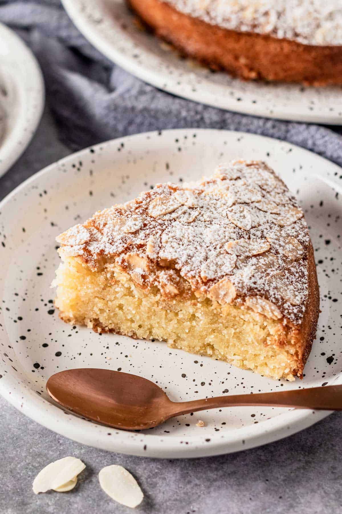 a slice of almond flour cake with flaked almonds and icing sugar on top