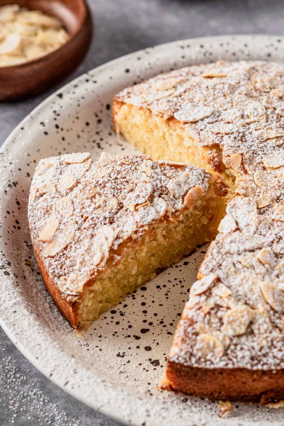 a slice of almond flour cake with flaked almonds and icing sugar on top
