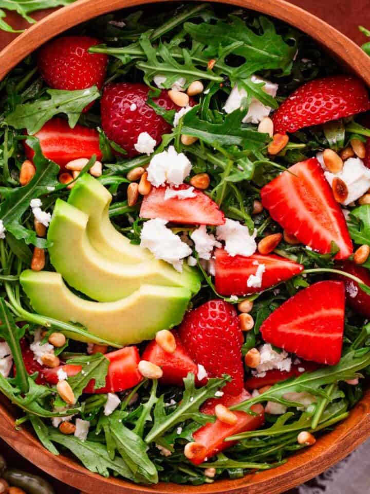 arugula salad with strawberries and feta in a bowl.