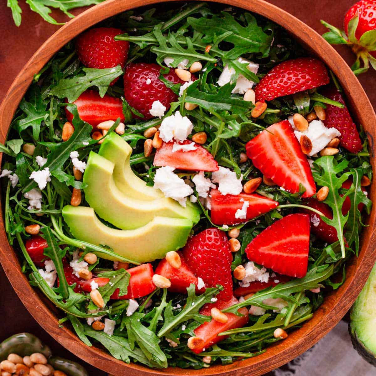 arugula salad with strawberries and feta in a bowl.