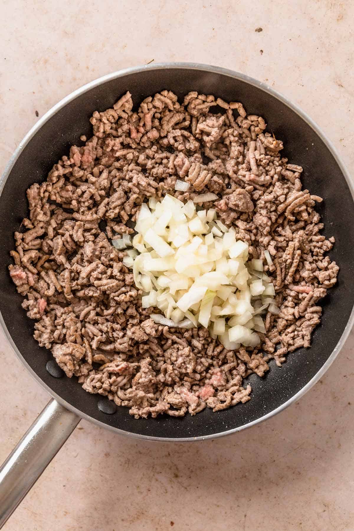 ground beef cooking with onion in a skillet