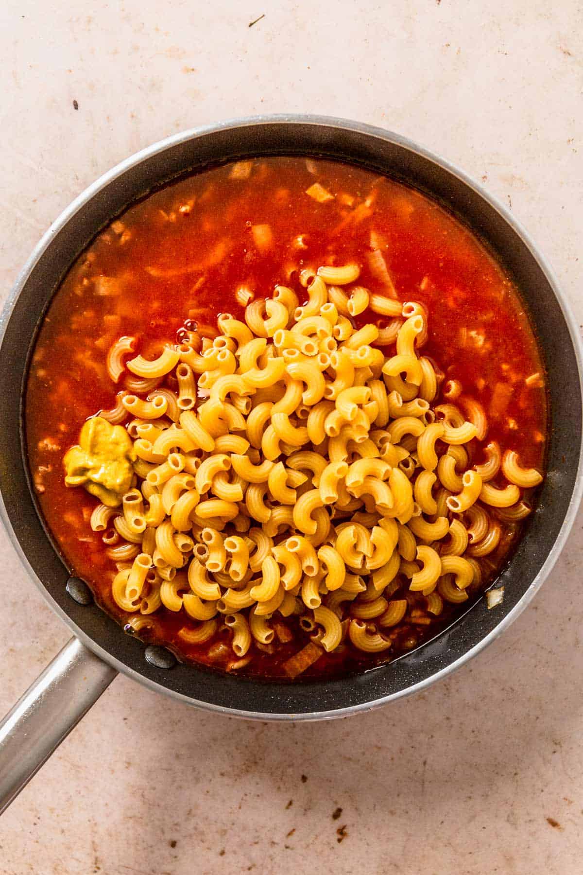 dry macaroni pasta added to tomato sauce