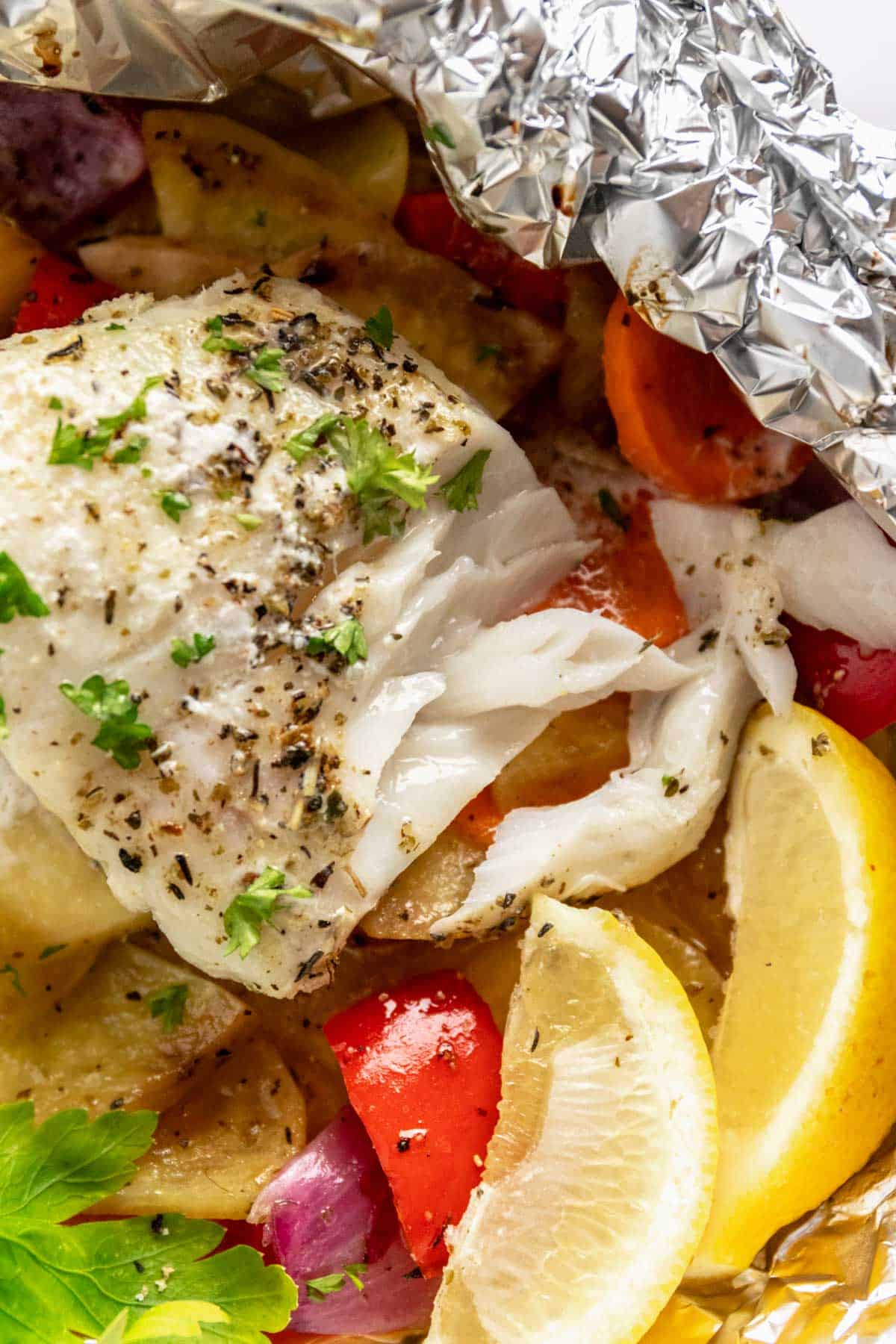 flaky baked cod fillets in foil with vegetables and lemon