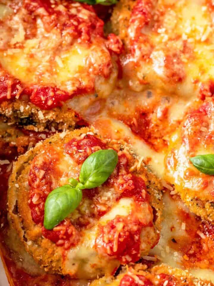 baked Eggplant Parmesan in baking dish with basil leaves.