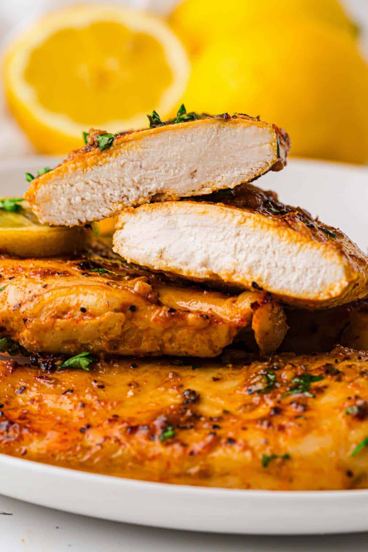 Sliced baked lemon chicken breasts stacked with golden crust and juicy interior.