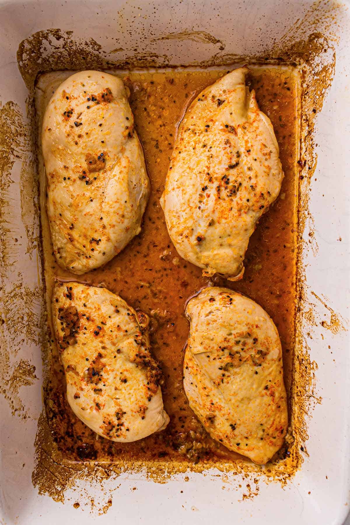 Lemon garlic chicken breasts baking in oven dish.