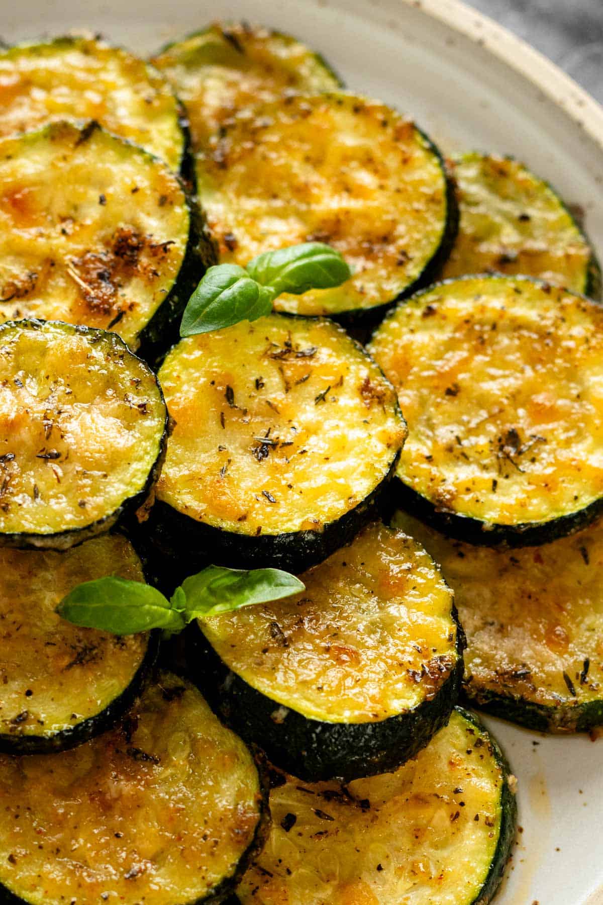 baked parmesan zucchini rounds garnished with fresh basil leaves.