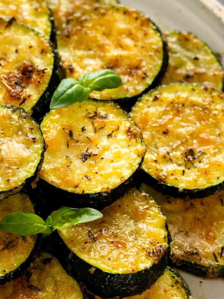 baked parmesan zucchini rounds garnished with fresh basil leaves.