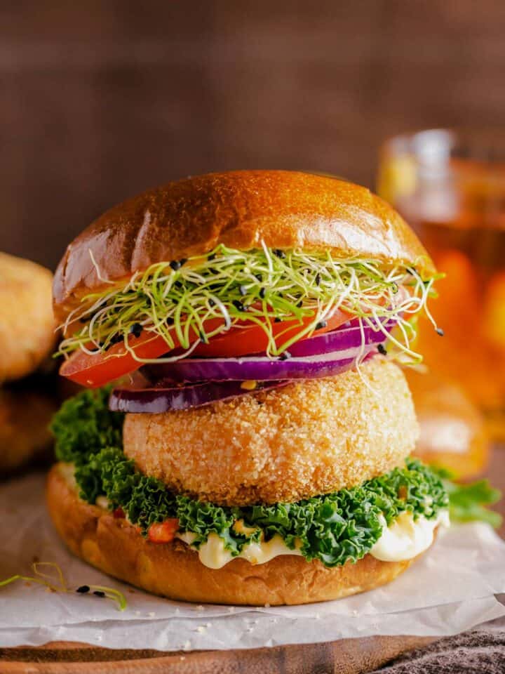 salmon patties served between burger buns, greens, tomato, red onion