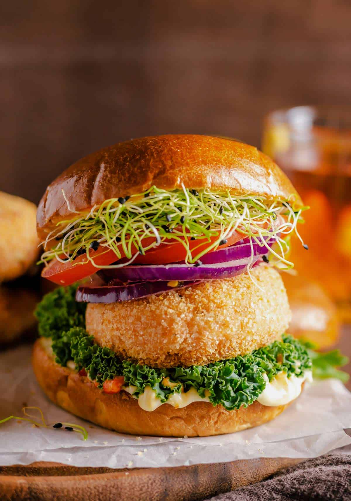 salmon patties served between burger buns, greens, tomato, red onion