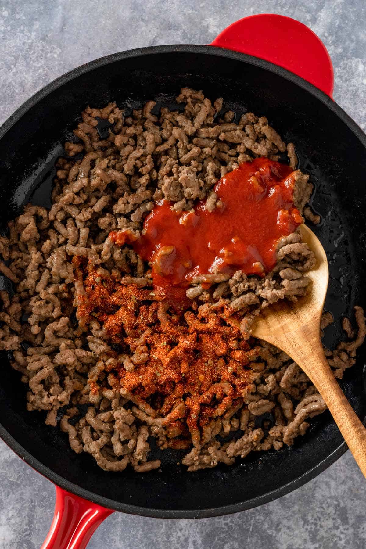 browned beef in skillet with tomato sauce and taco seasoning