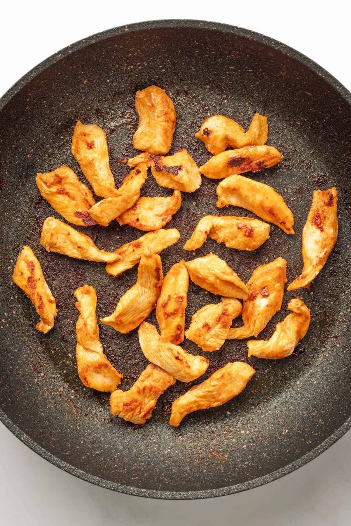 Buffalo chicken strips in saute pan.